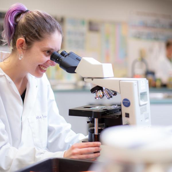 VIU student smiling and looking in a microscope