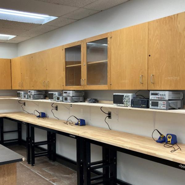 Student workbenches with function generator, multimeter, power supply, oscilloscope, and soldering station.